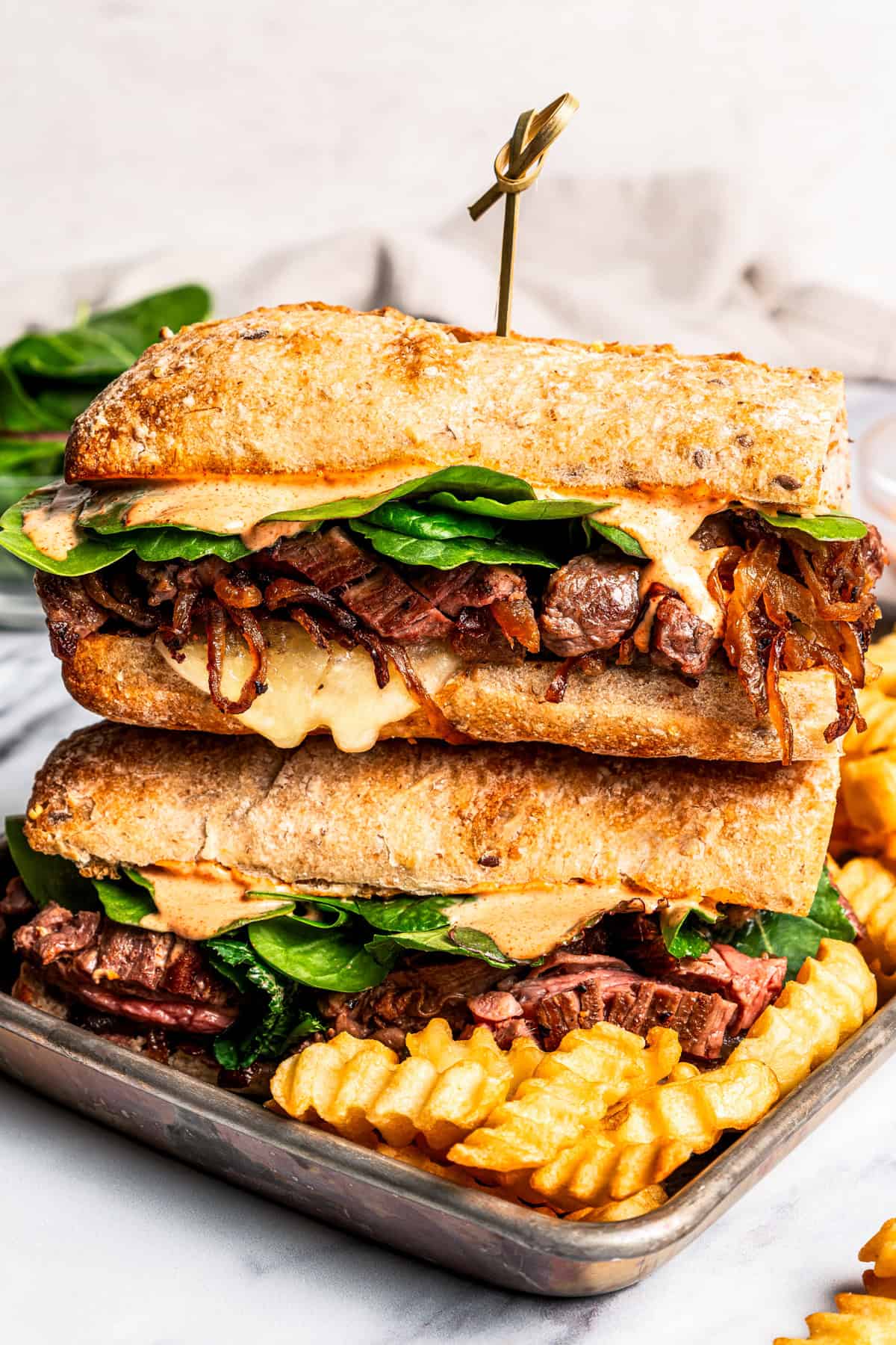 Two halves of a steak sandwich stacked on a tray.