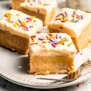 Four frosted sugar cookie bars served on a plate.