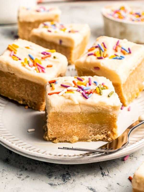 Four frosted sugar cookie bars served on a plate.