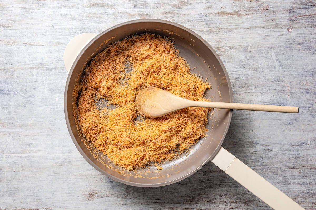 Toasted shredded phyllo pastry in a skillet with a wooden spoon.