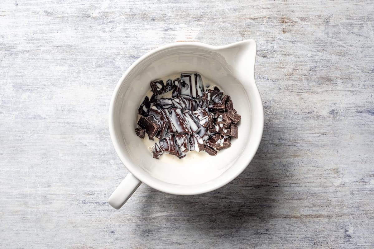 Chopped chocolate added to a bowl of warmed heavy cream.