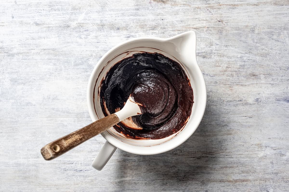 Chocolate ganache in a bowl with a spatula.