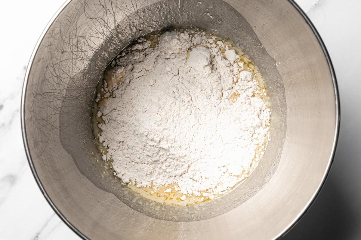 Flour is added to the wet ingredients in a bowl.