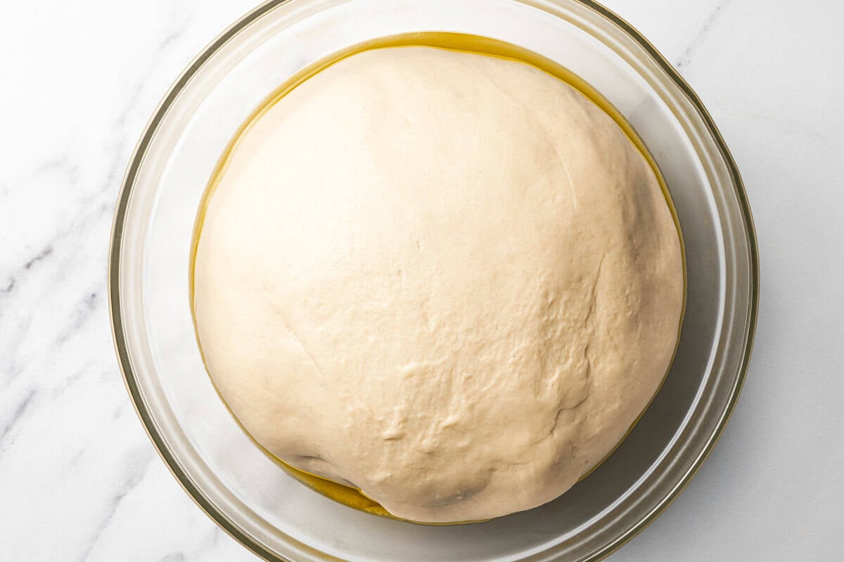 Risen dough in a bowl to be used for making dinner rolls.