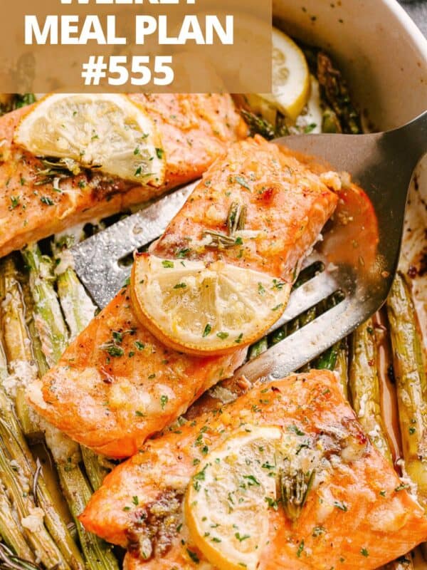 Baked salmon fillets in a baking dish with cooked asparagus.