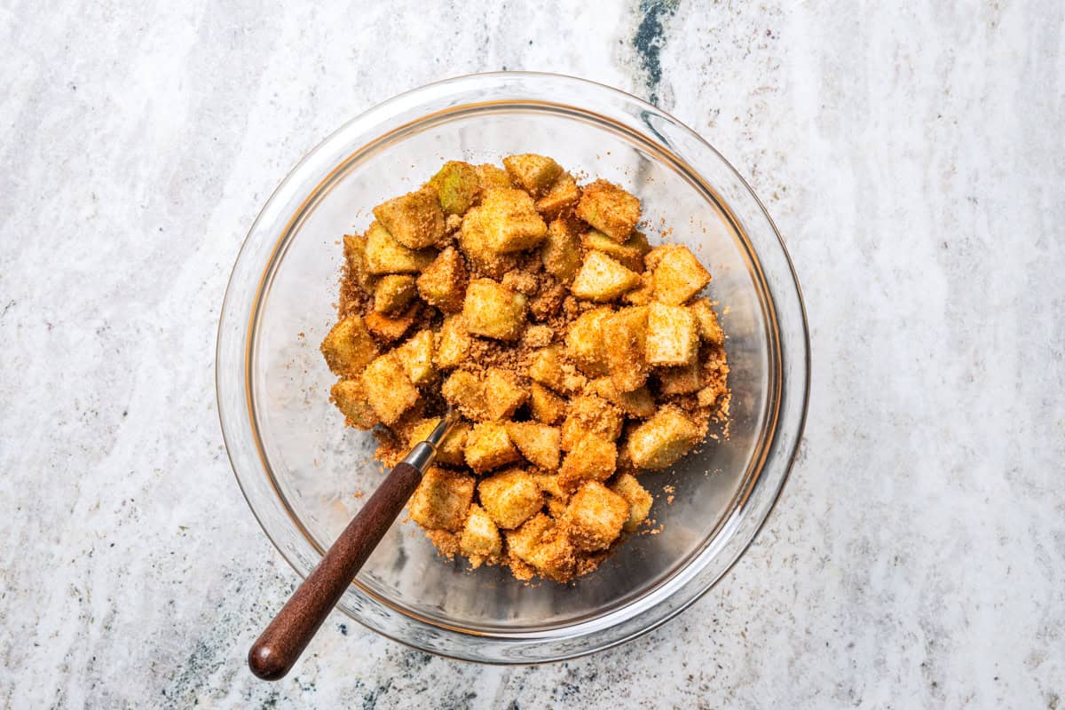 Chopped apples tossed with spices in a bowl.