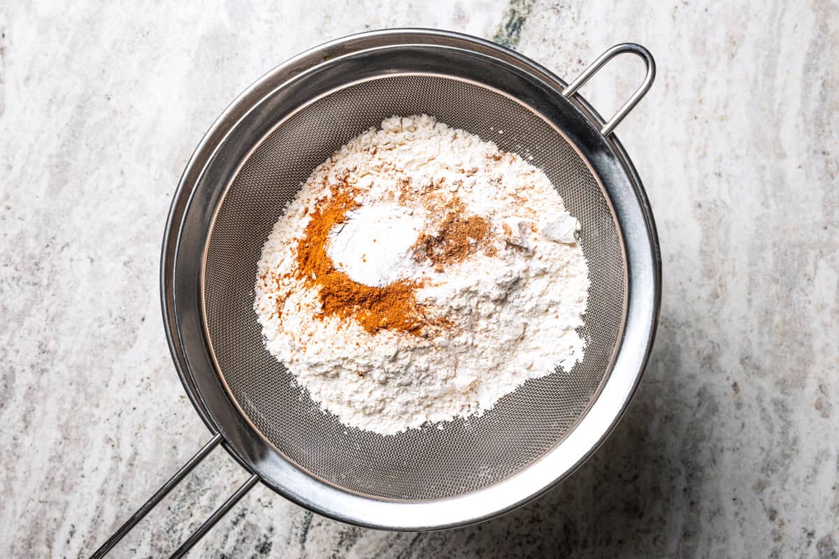 Dry ingredients in a sift held over the bowl of wet ingredients.