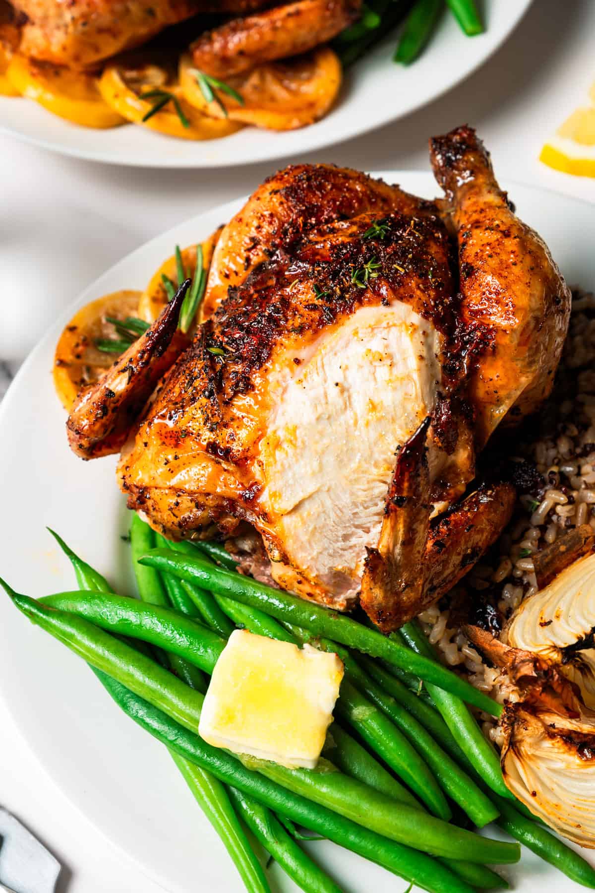 This easy Cornish hen recipe is perfectly juicy and golden-brown, rubbed with savory spices and oven-roasted over a bed of lemon and herbs. A cornish hen served over rice with a side of fresh green beans.