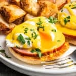 Eggs Benedict with the runny yolk oozing down the bacon and muffin.