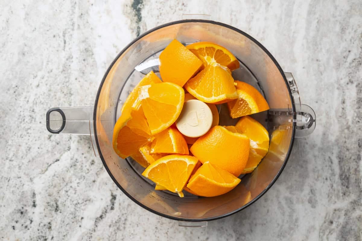 This orange cake recipe uses whole oranges, peels and all! It's moist and full of sweet citrus flavor, drenched in orange glaze. Orange quarters are added to a food processor.