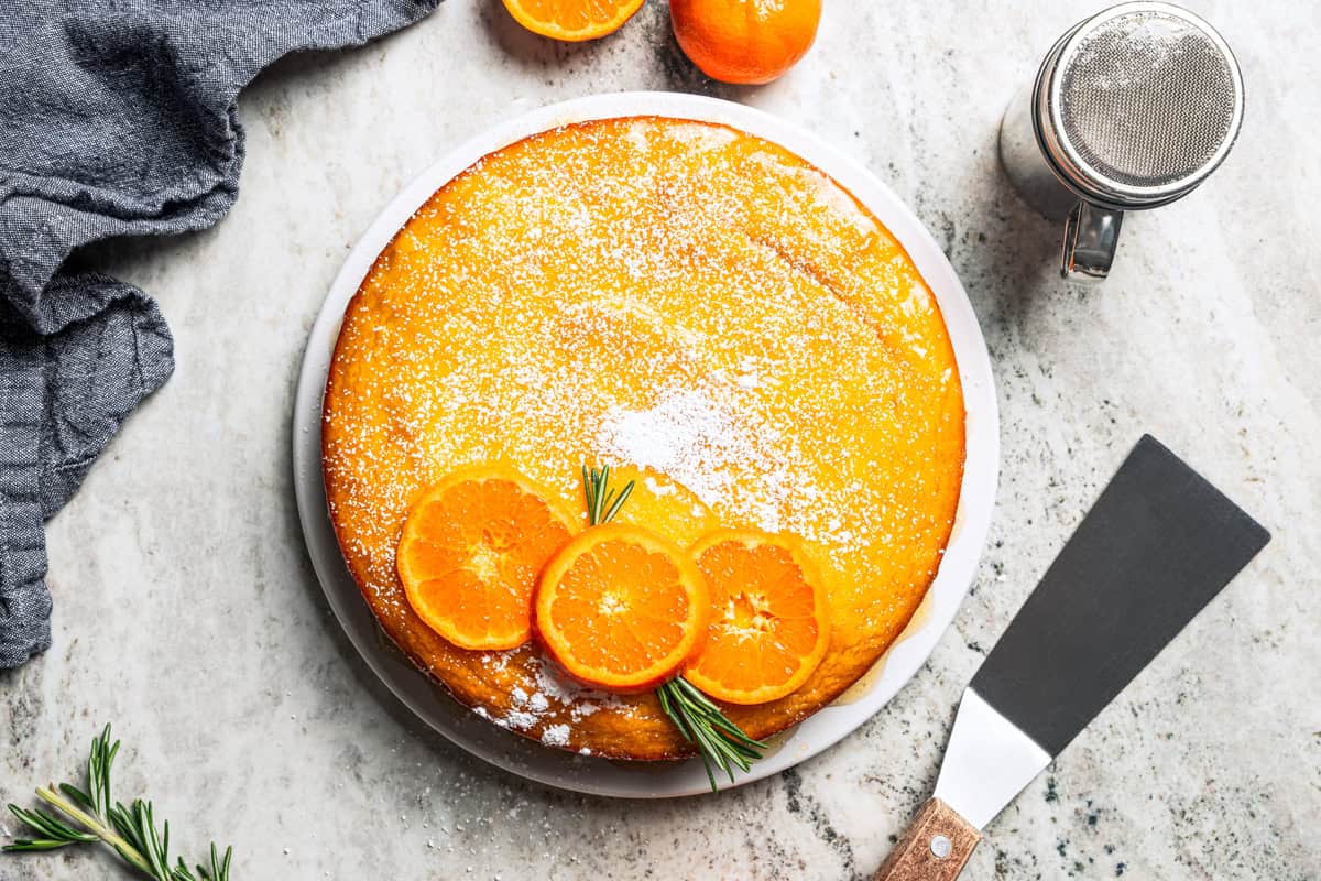This orange cake recipe uses whole oranges, peels and all! It's moist and full of sweet citrus flavor, drenched in orange glaze. An orange cake dusted with powdered sugar and topped with fresh orange slices.