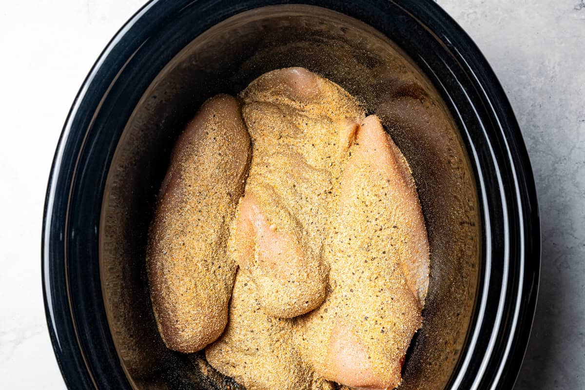 Seasoned chicken inside the slow cooker.