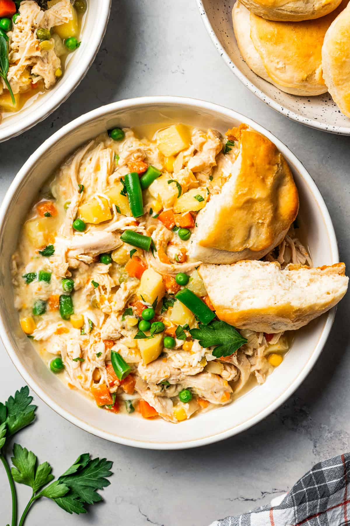 Slow cooked chicken pot pie in a bowl topped with a biscuit that's broken in half.