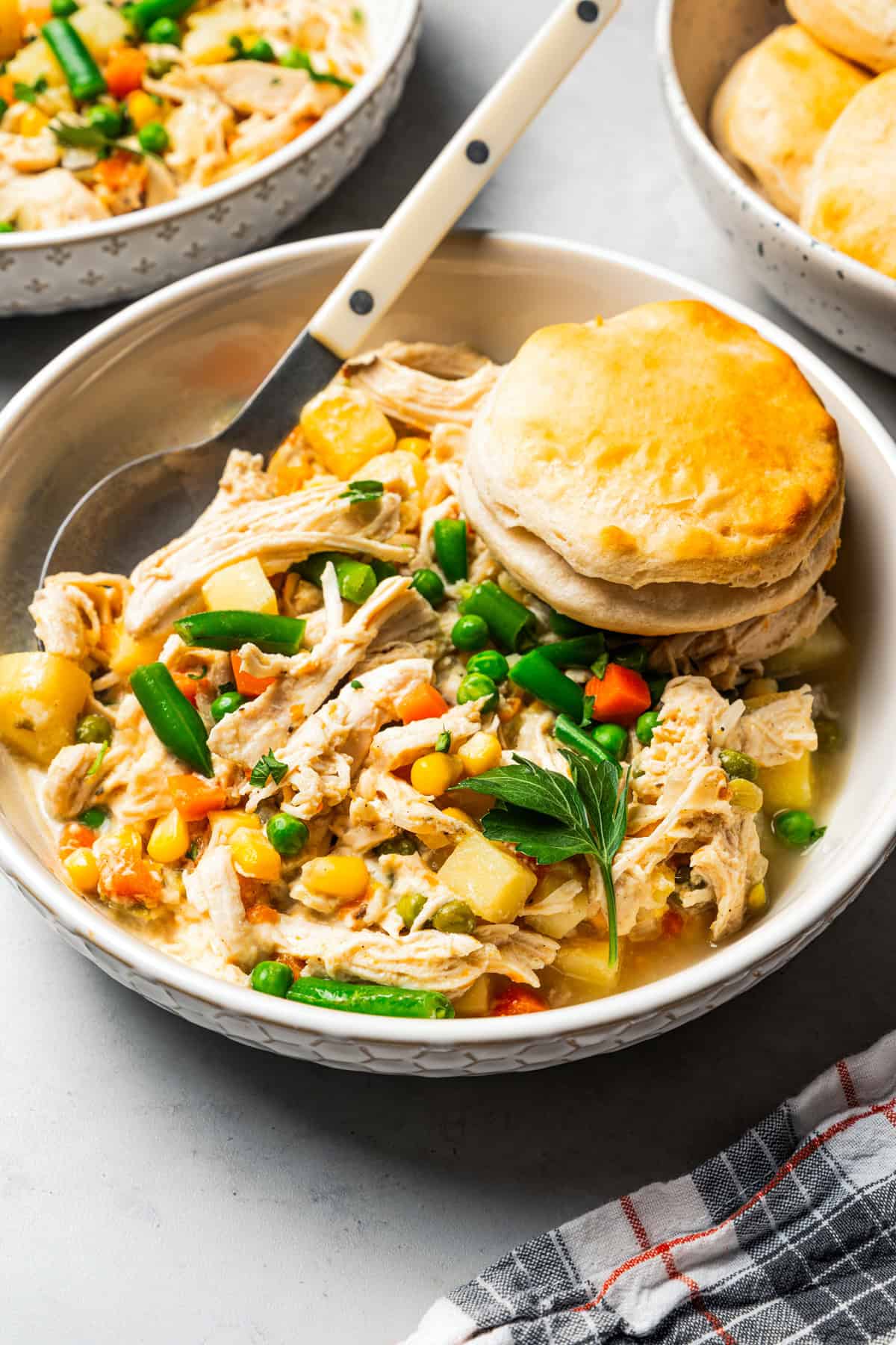 Slow cooker chicken pot pie in a bowl topped with a biscuit.