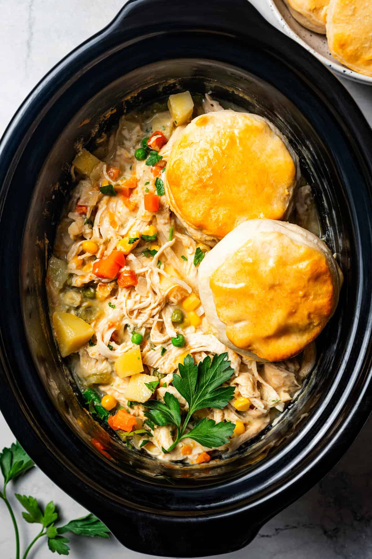 two biscuits on top of chicken pot pie in the slow cooker.