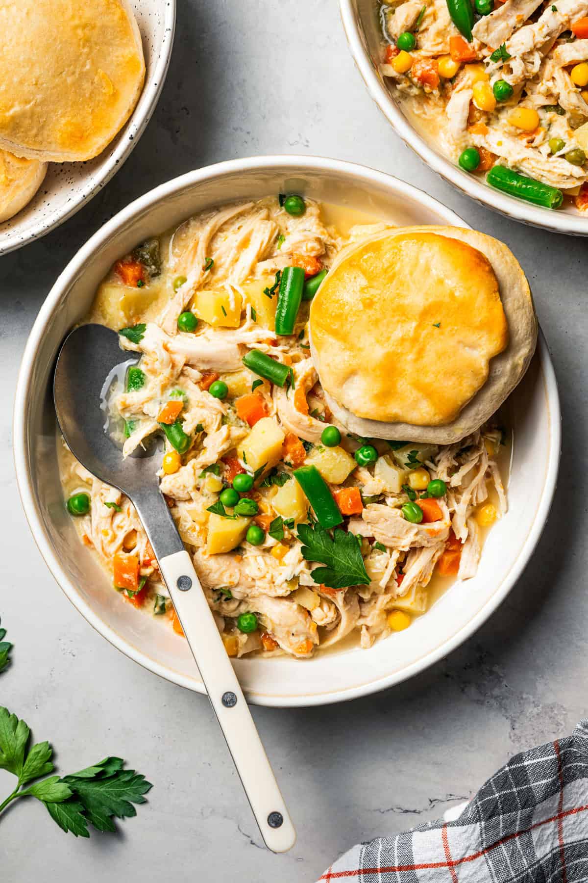 Chicken pot pie in a bowl topped with a biscuit that's broken in half.