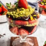 A dessert cup packed with sliced strawberries, chocolate syrup, and pistachio mixture to make Dubai chocolate strawberry cups.