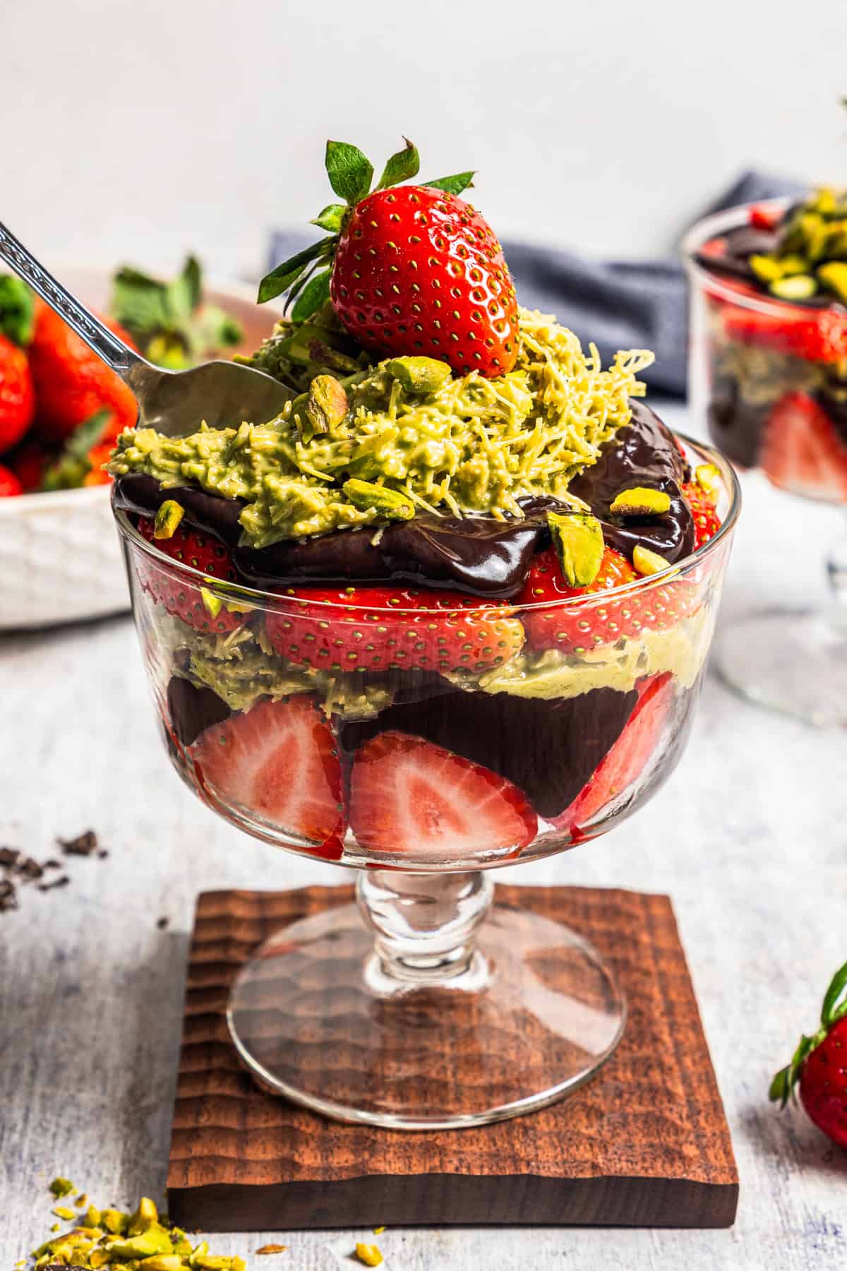 A dessert cup packed with sliced strawberries, chocolate syrup, and pistachio mixture to make Dubai chocolate strawberry cups.