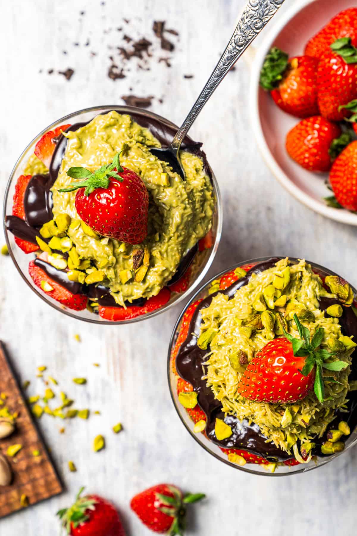 Top view of Dubai chocolate strawberry cups next to a bowl of fresh strawberries.