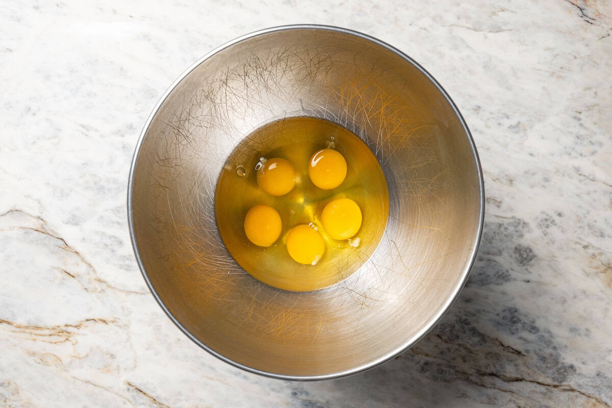 Five cracked eggs in a bowl.