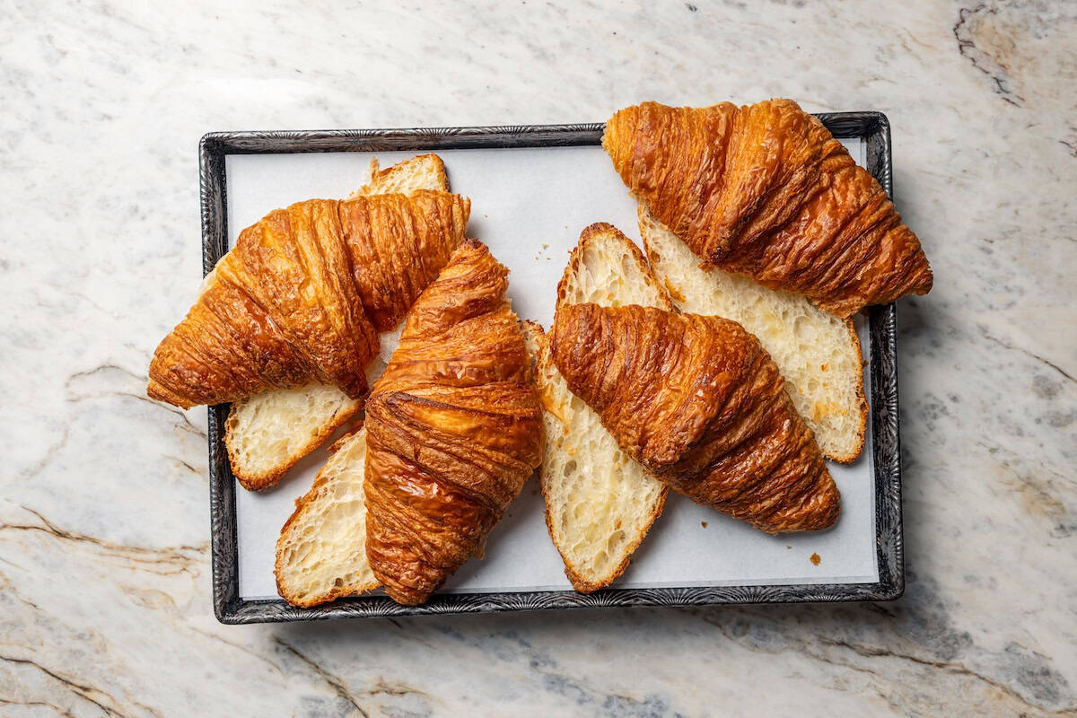 Croissants cut in half lengthwise on a baking sheet.