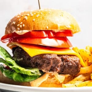An air fryer hamburger next to fries on a plate.