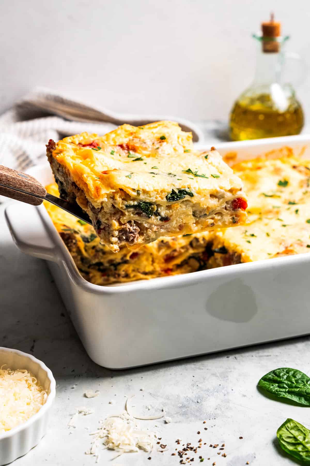 Lifting a slice of breakfast lasagna from a casserole dish.
