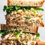 Two cottage cheese chicken salad sandwiches stacked on a wooden cutting board.
