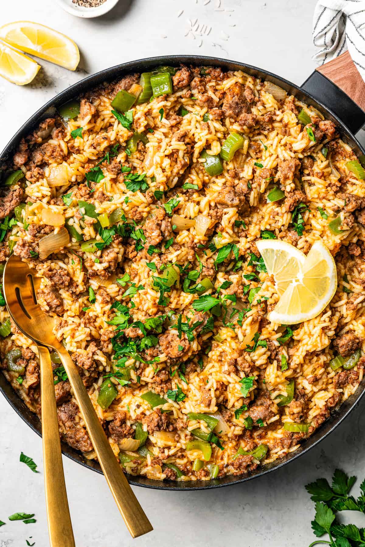 Dirty rice in a skillet with serving spoons.