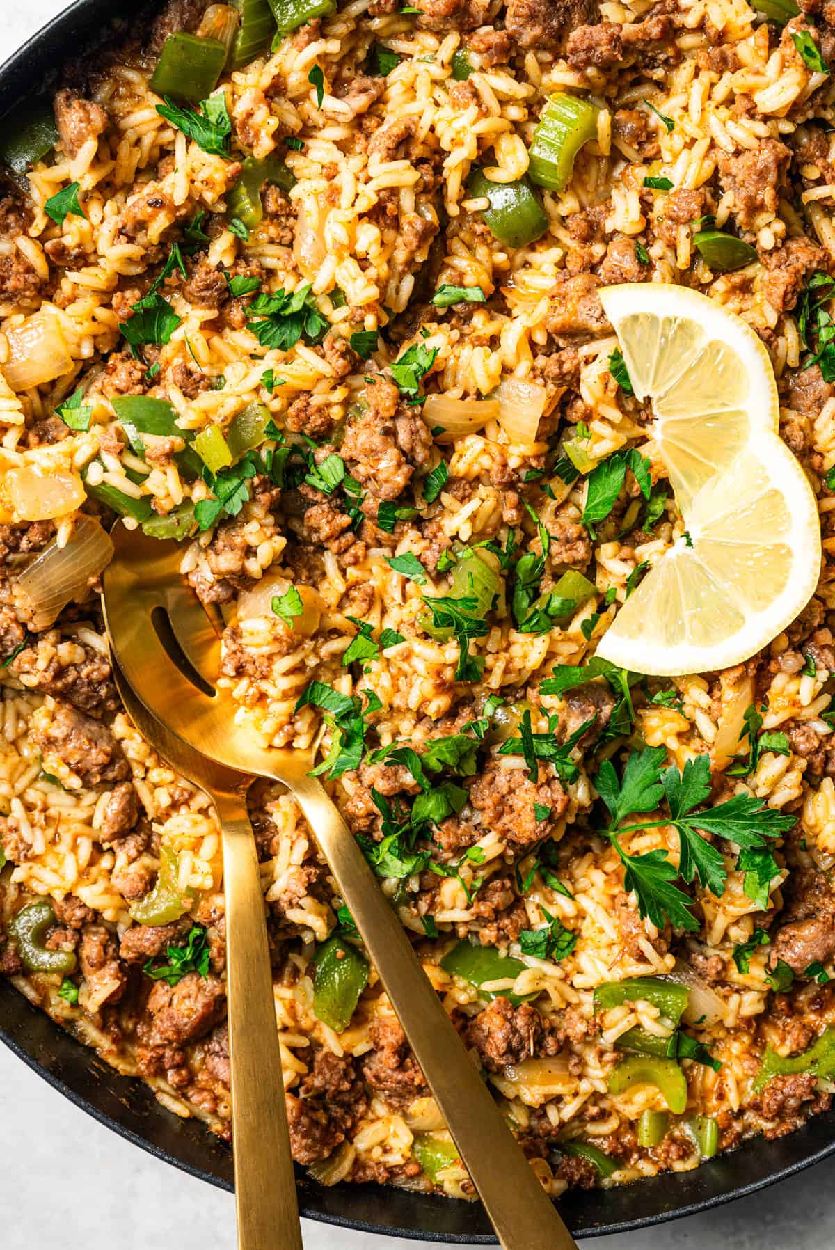 Dirty rice in a skillet with serving spoons.