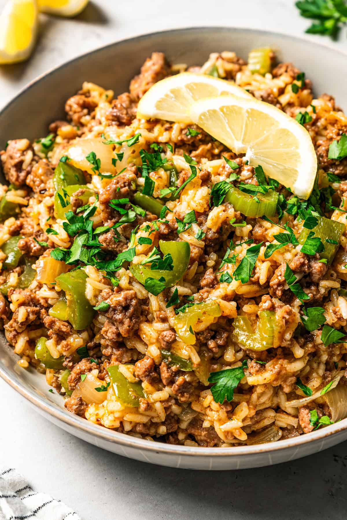 Dirty rice garnished with herbs and lemon slices in a bowl.