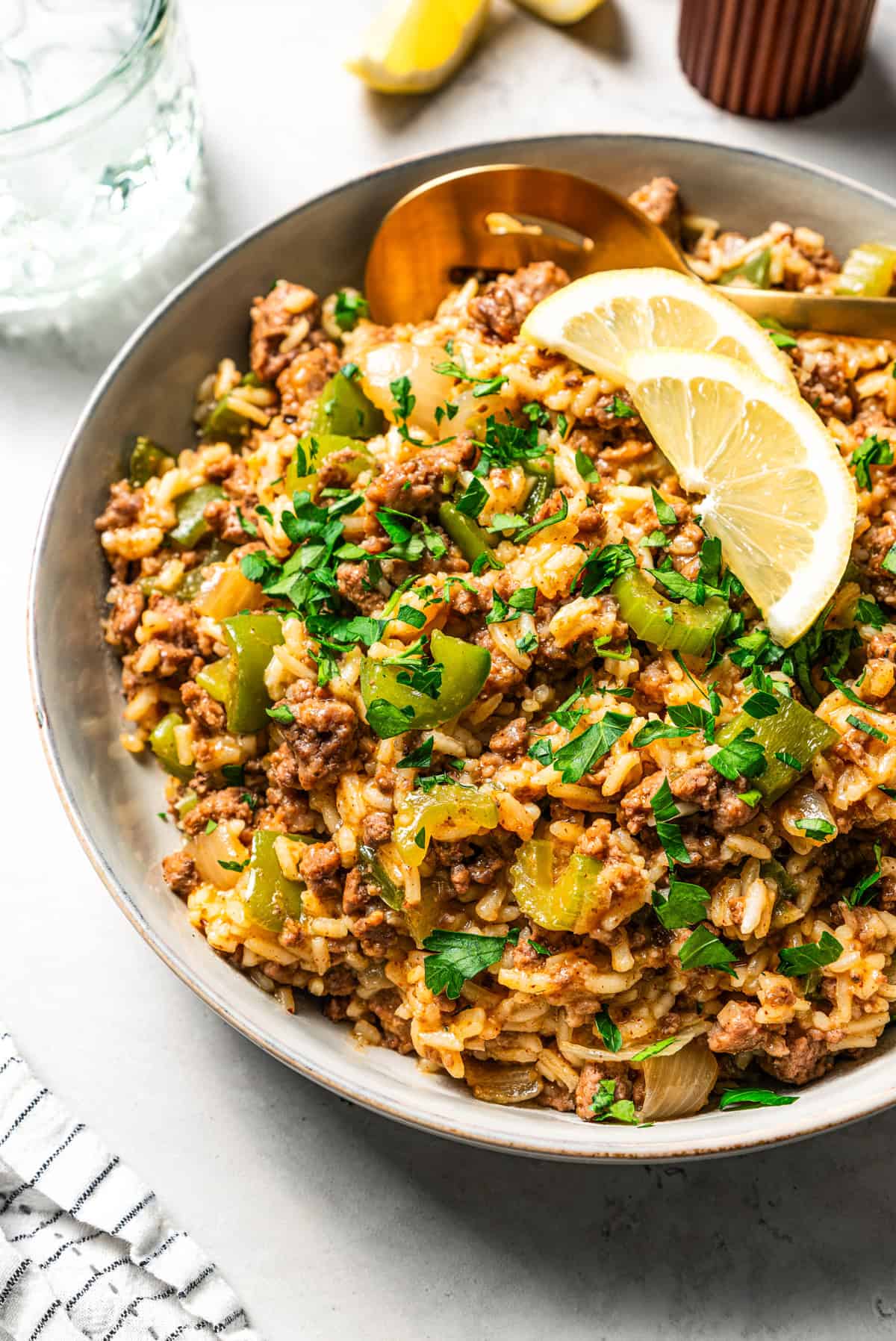 Weekly Meal Plan Dirty rice garnished with herbs and lemon slices in a bowl.