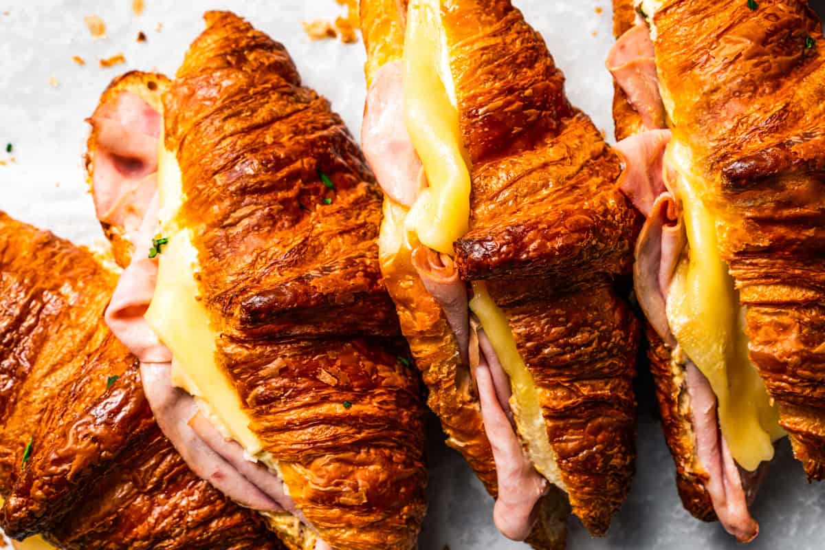 Four stacked ham and cheese croissant sandwiches.