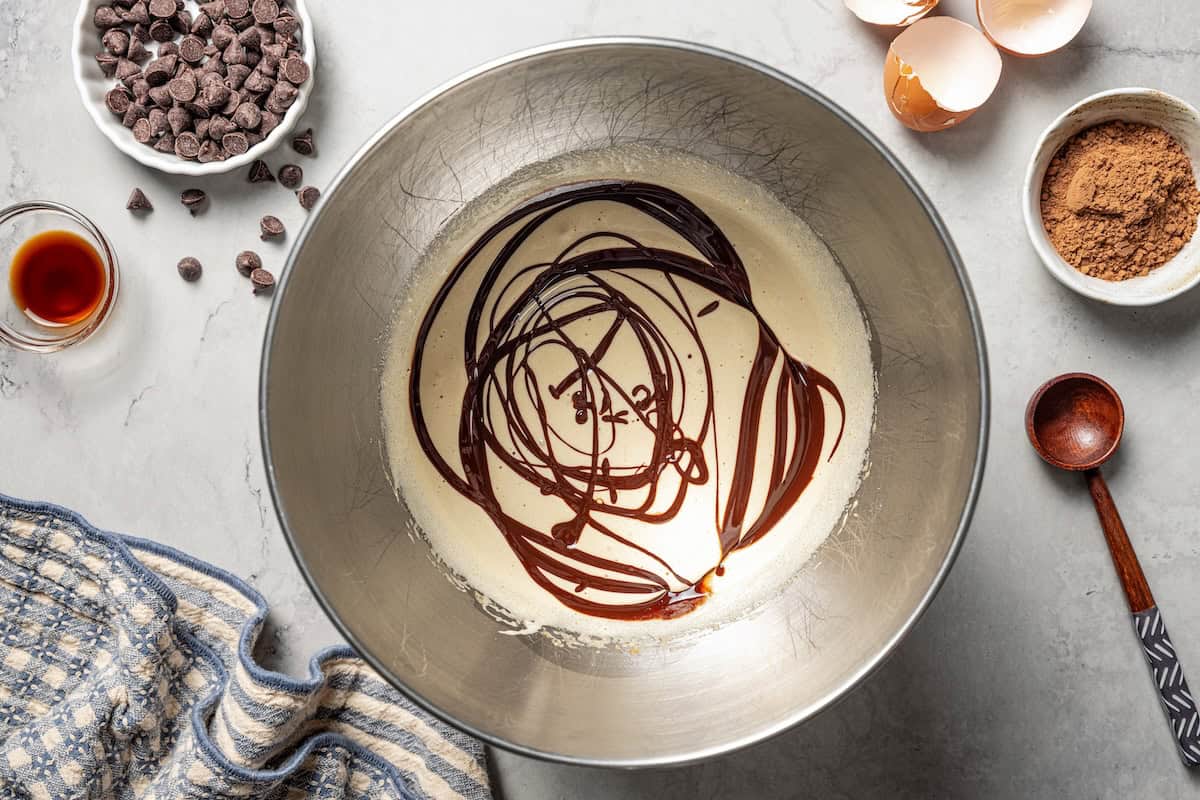 These chewy brownie cookies are the best of a fudgy brownie crossed with a soft-baked chocolate cookie! Made with real melted chocolate. Melted chocolate combined with the beaten eggs and sugar in a bowl.
