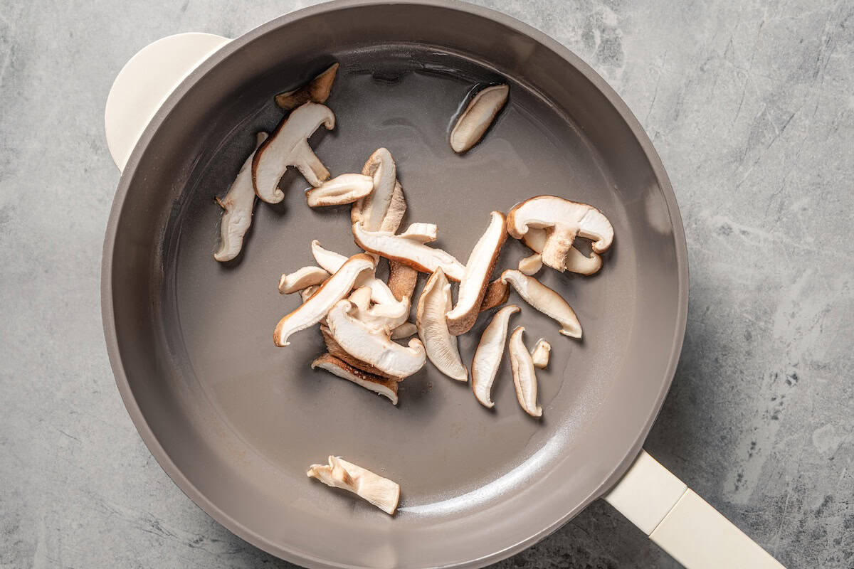 This quick and easy kimchi ramen recipe packs a spicy, savory punch with instant noodles, kimchi, shiitake mushrooms, and gochujang broth. Sliced shiitake mushrooms in a skillet.