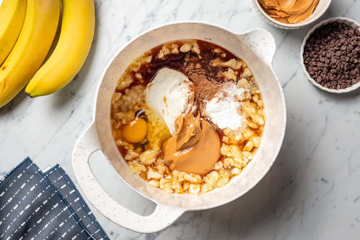 Peanut butter banana muffins are easy to make in one bowl! They’re super moist, with ripe bananas, creamy peanut butter, and chocolate chips. Wet peanut butter banana muffin batter ingredients combined in a bowl.