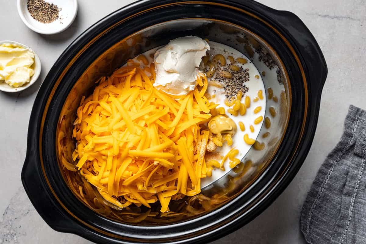 Ultra-creamy slow cooker mac and cheese is a dump-and-go version of my homemade mac and cheese recipe! Perfect for potlucks and holidays. Shredded cheese added to the rest of the mac and cheese ingredients in the slow cooker.