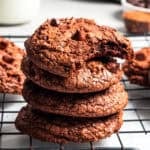 A stack of four brownie cookies, with the top one missing a bite.