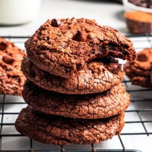A stack of four brownie cookies, with the top one missing a bite.