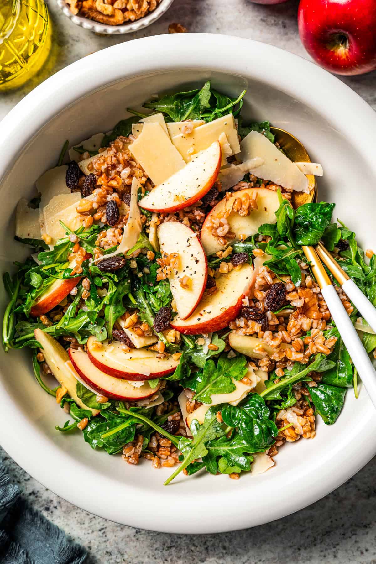 Farro salad with arugula, apples, parmesan, walnuts, and maple vinaigrette served in a bowl.