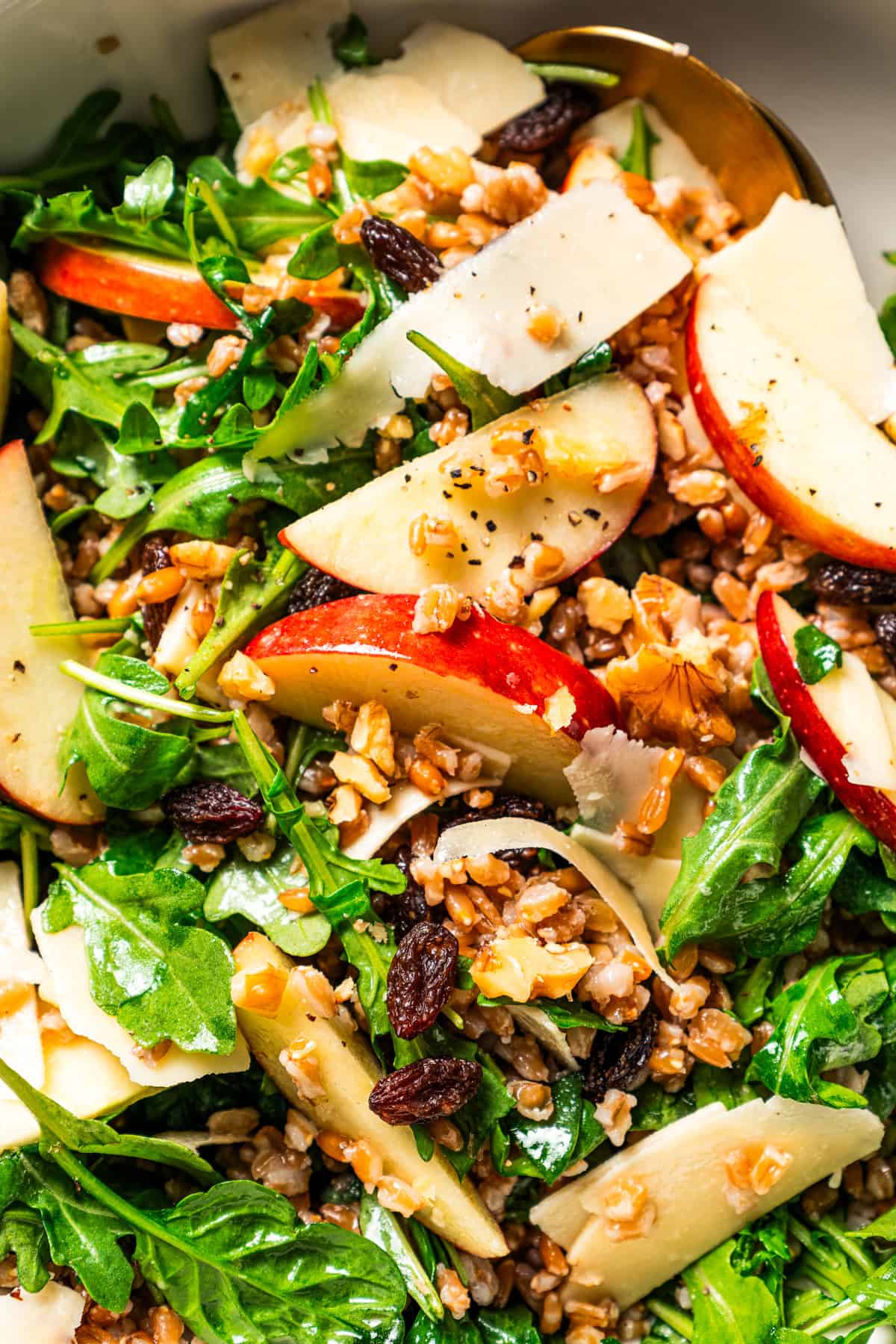 Farro salad with arugula, apples, parmesan, walnuts, and maple vinaigrette served in a bowl.