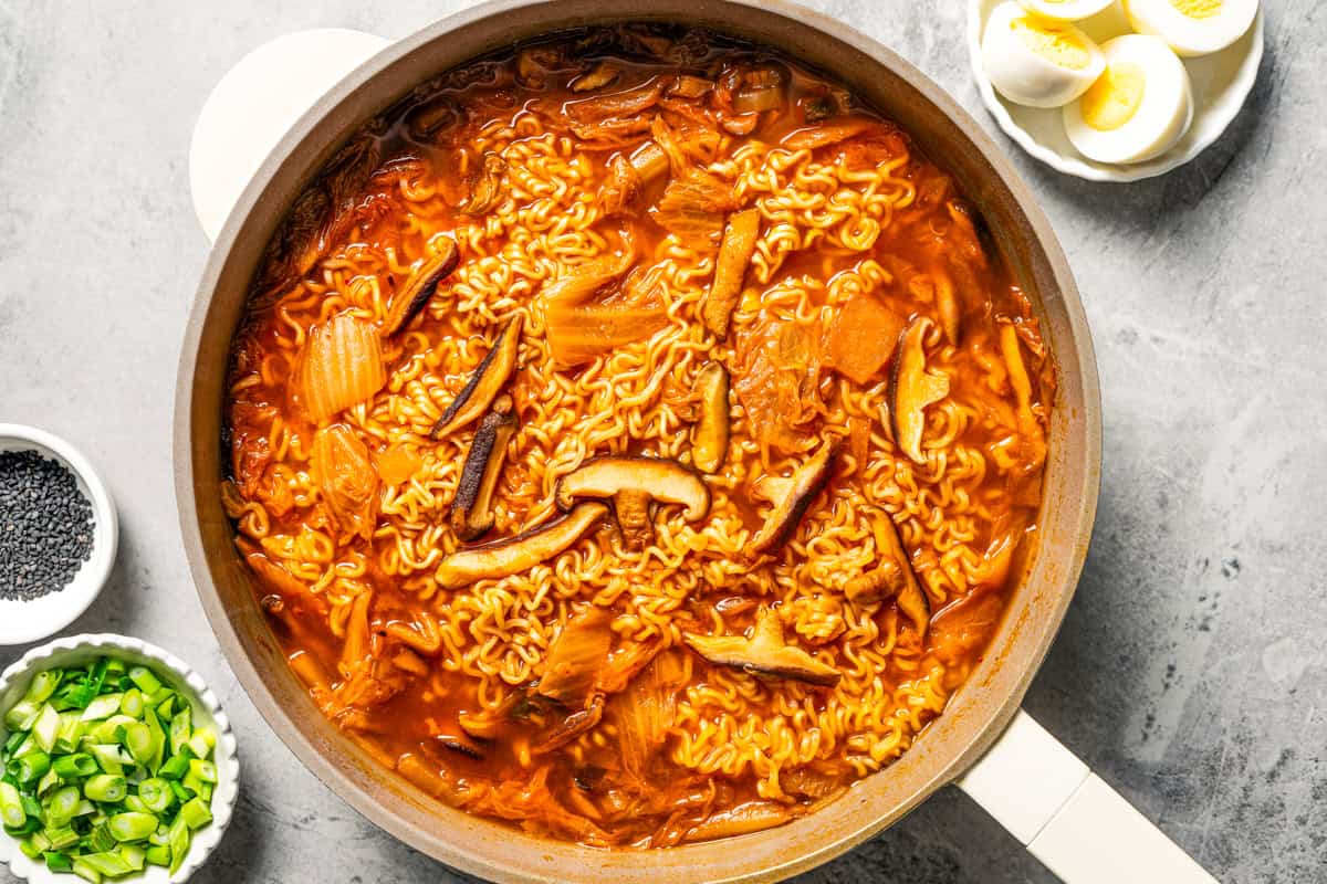 This quick and easy kimchi ramen recipe packs a spicy, savory punch with instant noodles, kimchi, shiitake mushrooms, and gochujang broth. Spicy kimchi ramen noodles in a skillet.