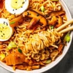 Chopsticks rolled in noodles in a bowl of kimchi ramen.
