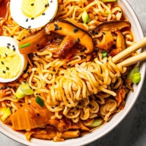 Chopsticks rolled in noodles in a bowl of kimchi ramen.