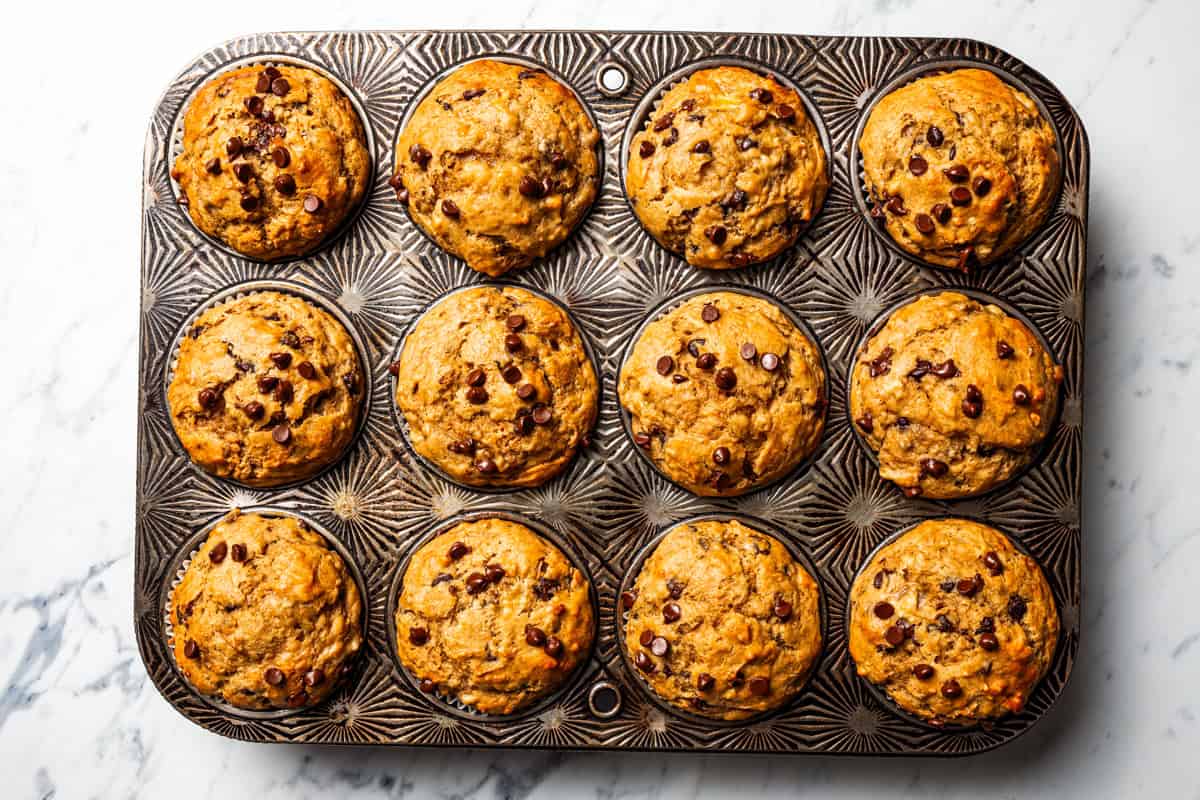 Peanut butter banana muffins are easy to make in one bowl! They’re super moist, with ripe bananas, creamy peanut butter, and chocolate chips. Baked peanut butter banana muffins in a muffin pan.