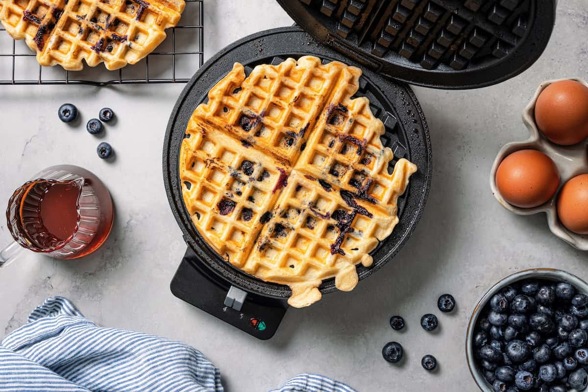 These classic blueberry waffles are light, fluffy, and ready in minutes. Rest the batter, then cook until they're golden brown and crisp. A crispy, golden blueberry waffle inside the waffle maker.
