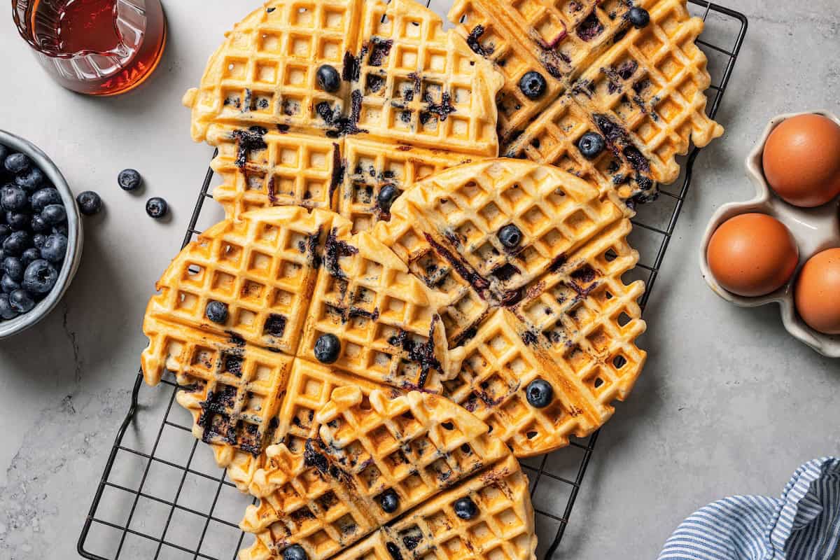 These classic blueberry waffles are light, fluffy, and ready in minutes. Rest the batter, then cook until they're golden brown and crisp. Crisp blueberry waffles on a wire rack.