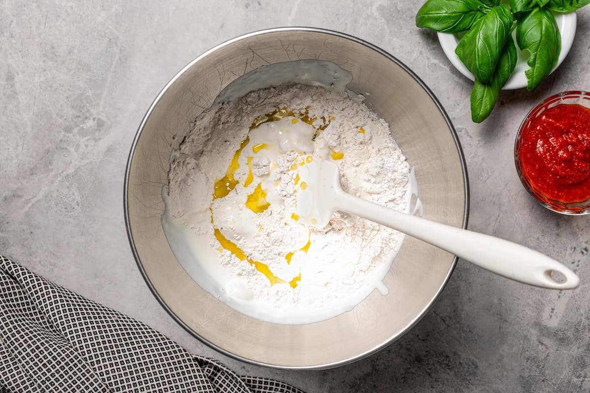 Olive oil and flour added to blended cottage cheese in a bowl.