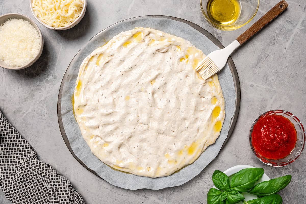 Brushing the edges of cottage cheese pizza dough with olive oil.
