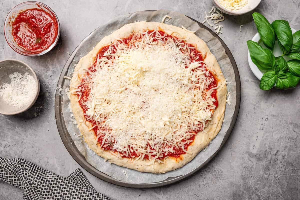 Shredded mozzarella and Parmesan cheese added on top of pizza sauce on a cottage cheese pizza crust.